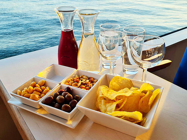 Rot- und Weißwein zusammen mit ausgewählten Snacks und Chips, die beim Sunset Cruise gereicht werden.