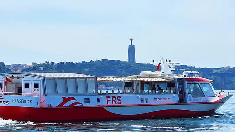 The boat on the Tagus River, cruising in the direction of the bridge Ponte 25 de Abril and the statue of Christ the King.