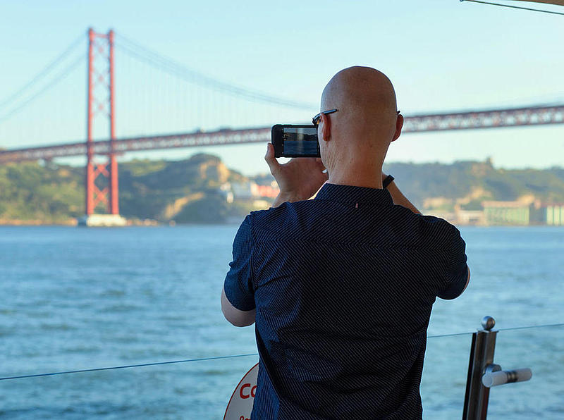 Ein Mann macht ein Foto von der Hängebrücke Ponte 25 de Abril.