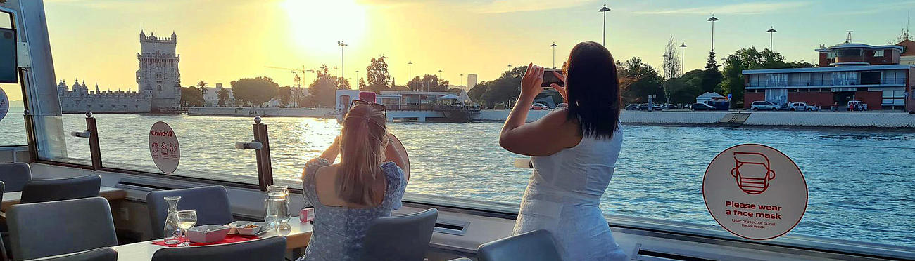 Zwei Frauen auf dem Schiff fotografieren den Turm von Belém in der Abendsonne.