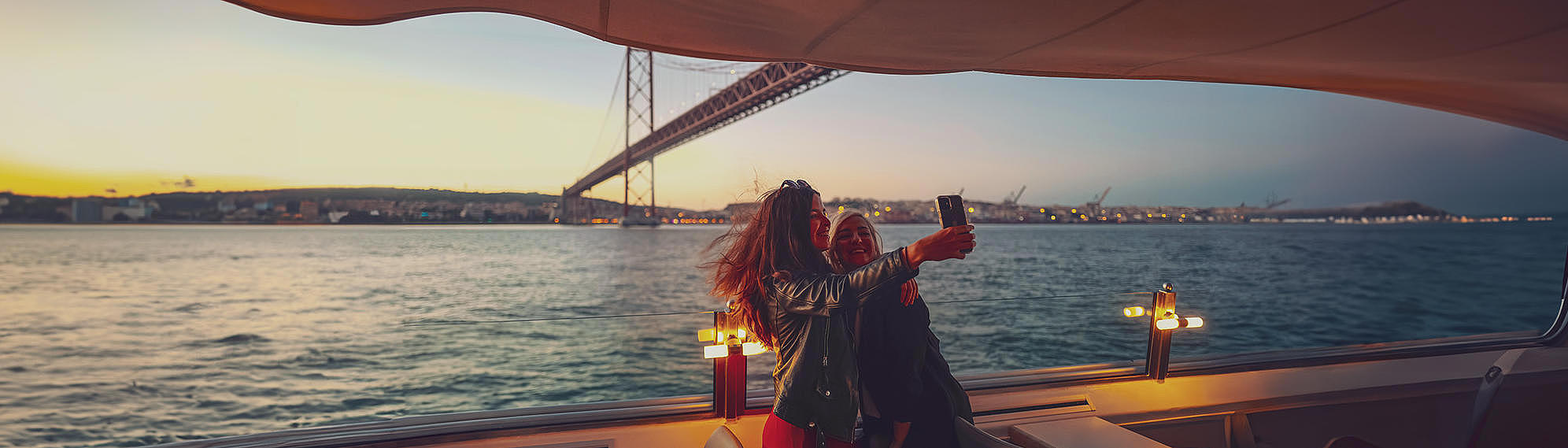 FRS Portugal sunset cruise two woman taking a selfie in front of ponte abril 25