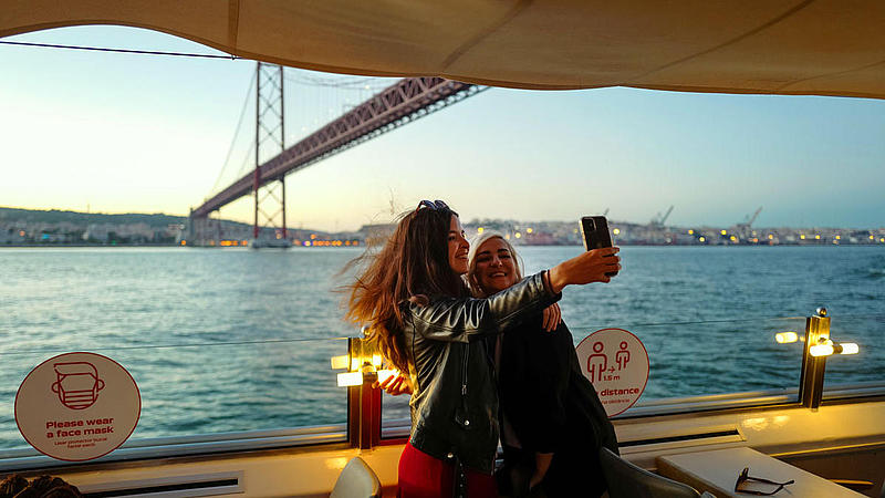 Zwei Frauen machen ein Selfie auf dem Schiff vor der Brücke des 25. April.