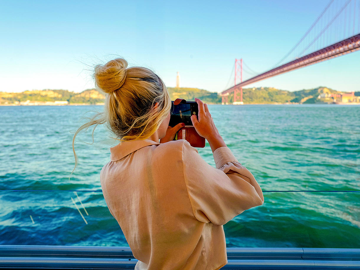 A woman on a boat takes a photo during the FRS Portugal Day Cruise