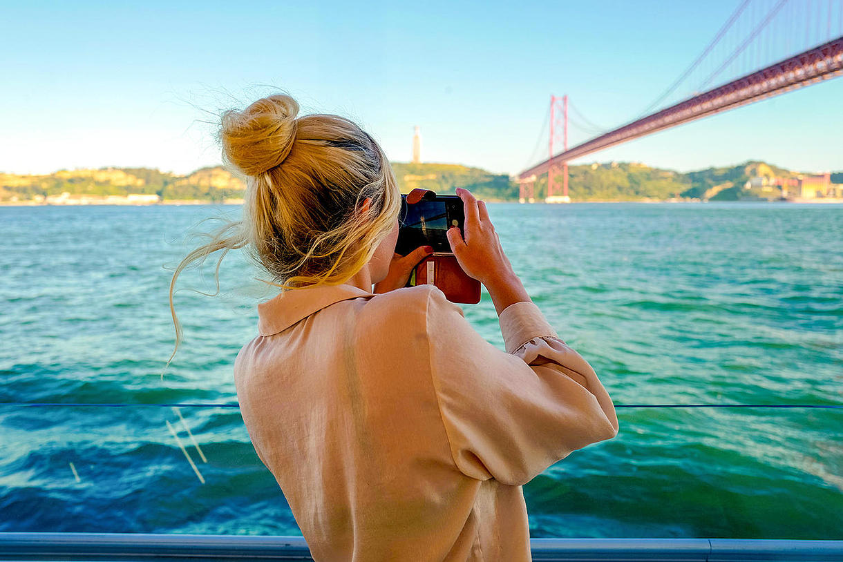 Uma mulher tira uma fotografia a bordo de um barco durante o cruzeiro de um dia da FRS Portugal.