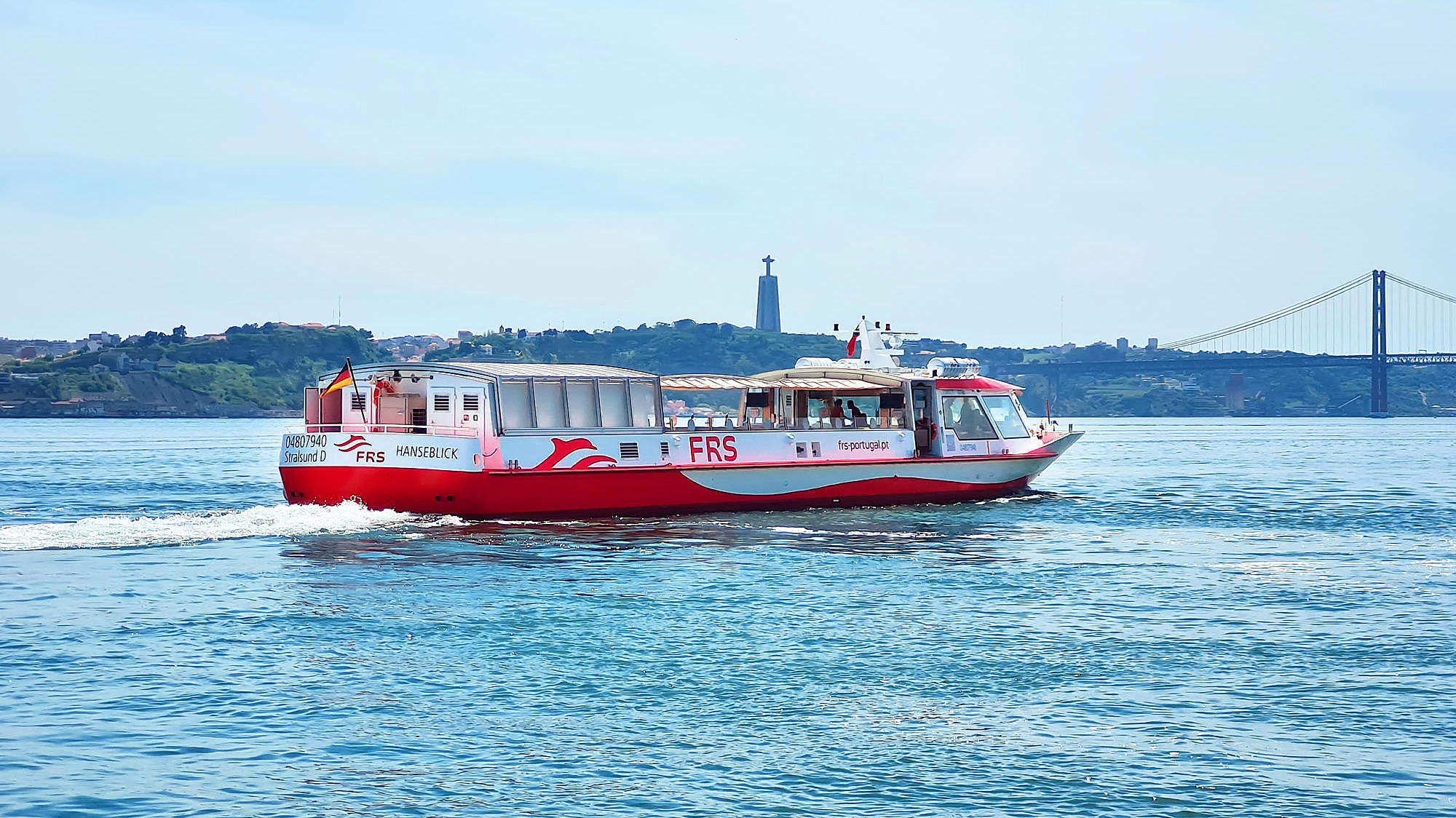 Vessel cruising on the Tagus river, Cristo Rei and the Ponte 25 de Abril in the background.
