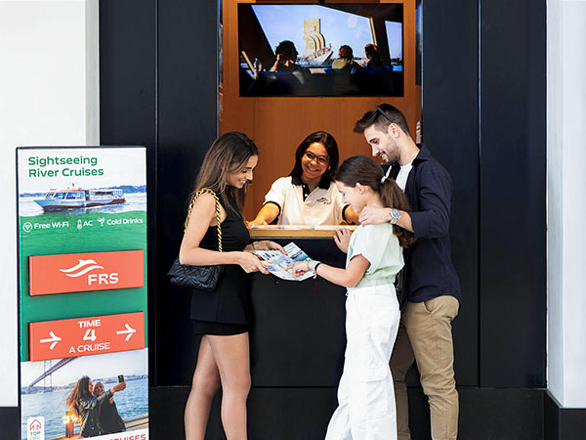 Young couple with child standing at the FRS Portugal ticket counter in the terminal.