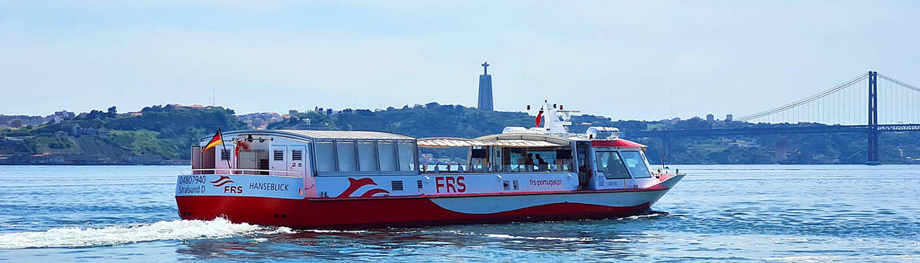 The boat on the Tagus River, cruising in the direction of the bridge Ponte 25 de Abril and the statue of Christ the King.