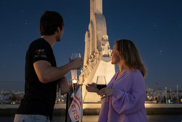 Um casal a ficar do lado de fora no escuro a beber vinho e a segurar uma bandeira FRS