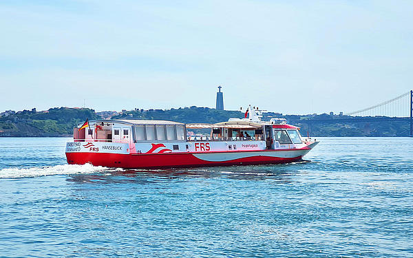 Schiff fährt auf dem Tagus, Christus-Statue und die Brücke des 25. April im Hintergrund.