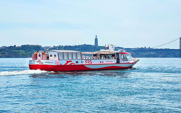 Schiff fährt auf dem Tagus, Christus-Statue und die Brücke des 25. April im Hintergrund.