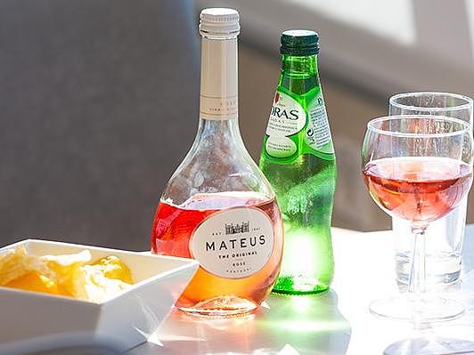 Vinho e uma tigela de batatas fritas numa mesa.