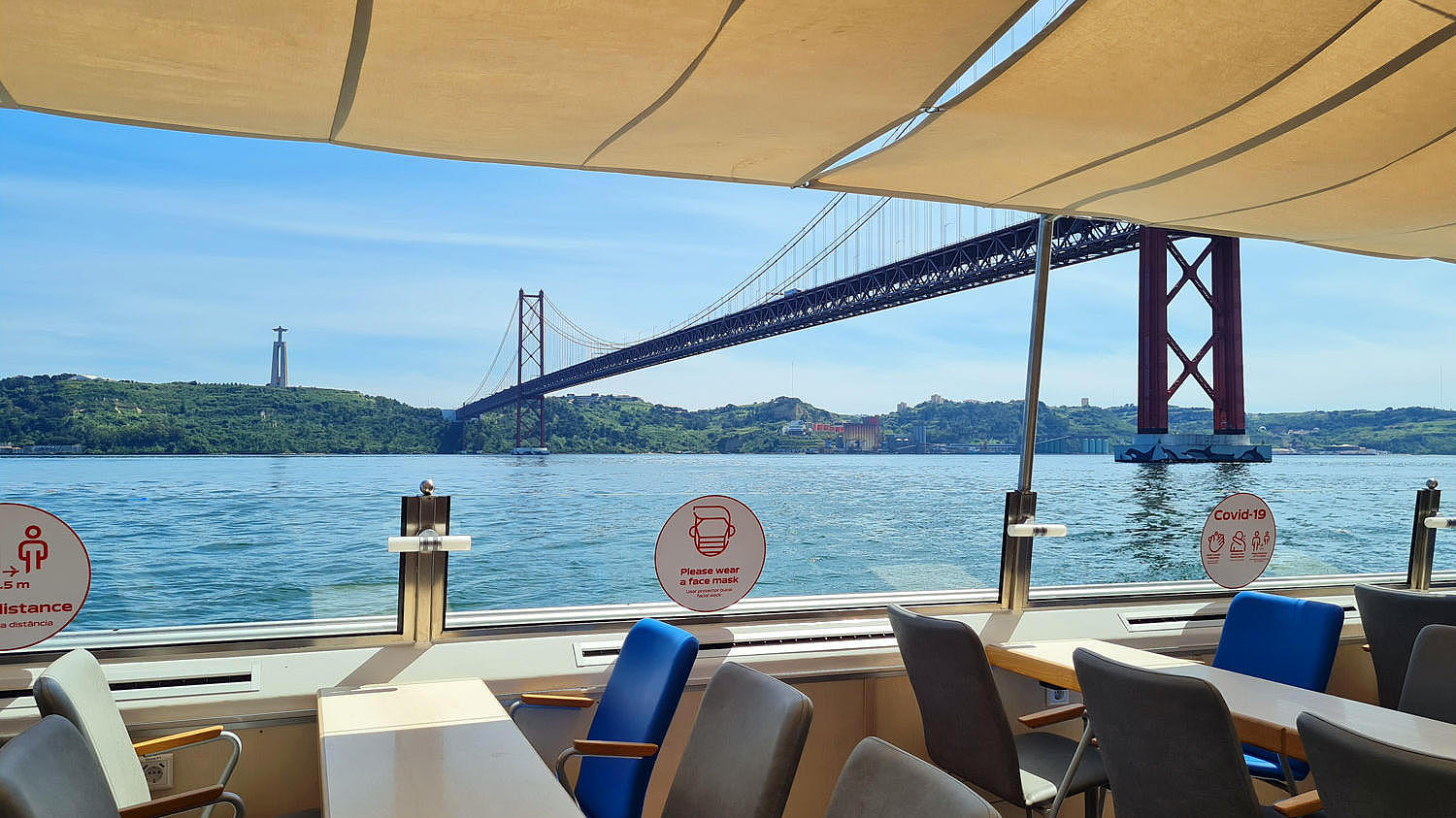 View from the vessel on the Tagus River, the bridge Ponte 25 de Abril as well as the statue of Cristo Rei.