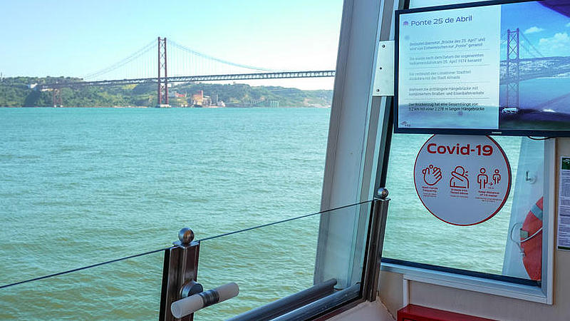 Screen on the vessel with information about the bridge 25 de Abril with the actual bridge in the background.