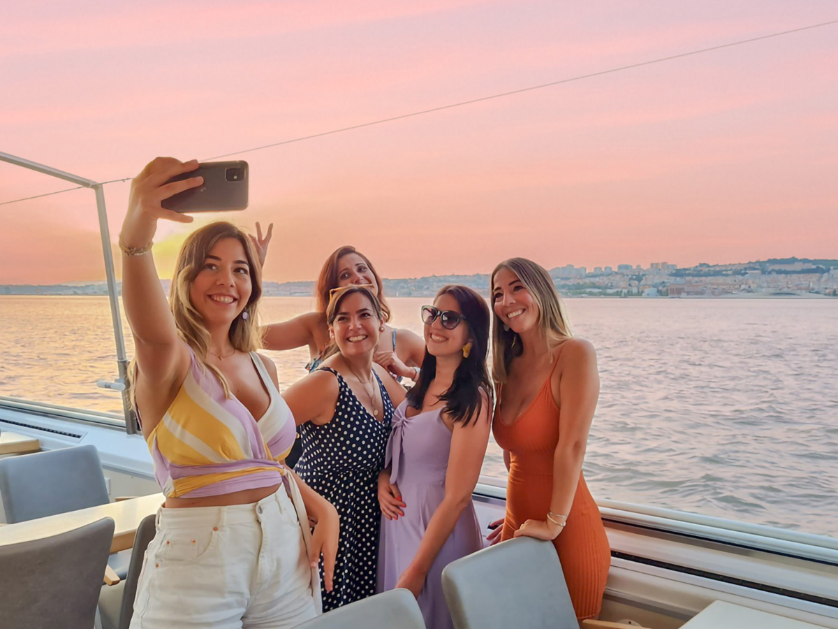Um grupo de jovens mulheres num barco tira uma selfie durante um cruzeiro ao pôr do sol da FRS.